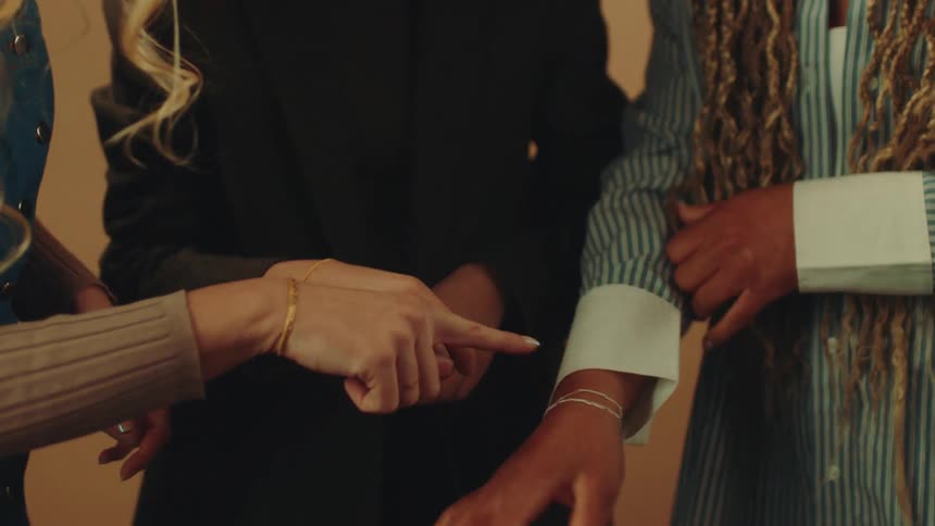 Three women standing next to each other showing off their bracelets on their wrists