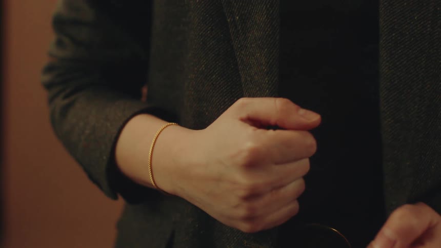Pair of womans hands with closed fists holding onto a coat