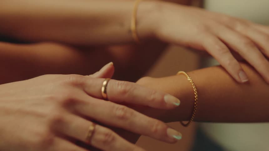 Closeup of three womens arms with bracelets and rings