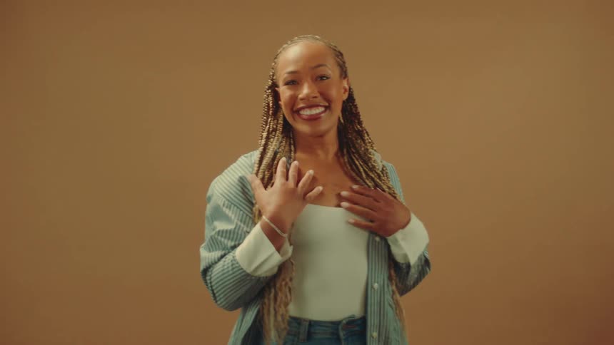 The woman is smiling and looking at her hand and the sleeve of her shirt