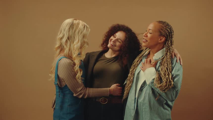 Three close friends are smiling and laughing as they hug