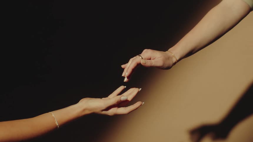 Two women touch hands while modeling jewelry