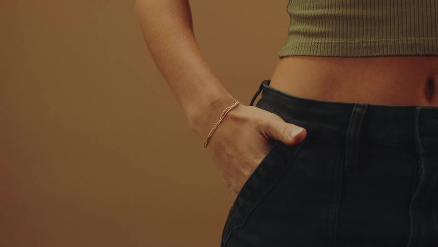 Woman is wearing a bracelet and has her hand in jean pocket