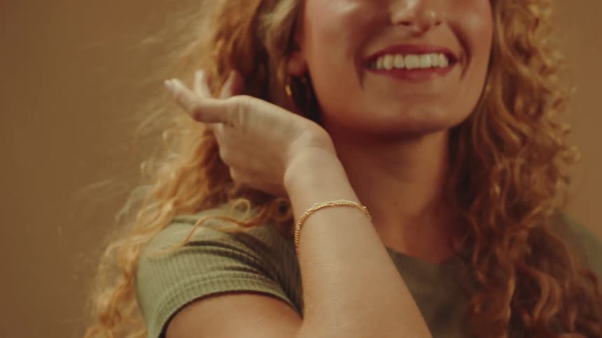Happy curly haired blonde model modeling gold bracelet