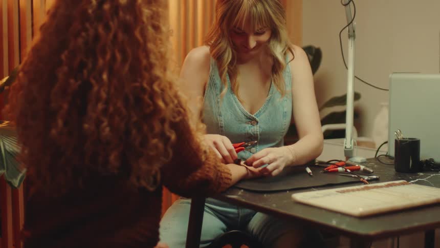 Woman putting an accessory on another womans wrist