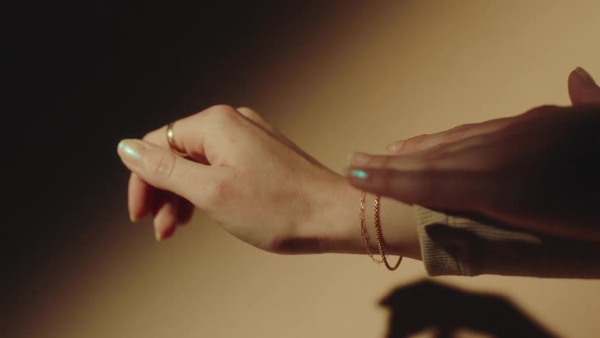 A model is touching the jewelry on her wrist