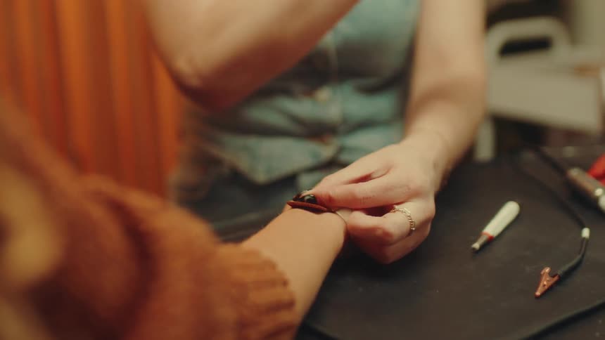 Pair of hands with pliers handling a persons wrist with an attachment