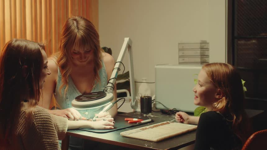Woman soldering a bracelet onto a teenage girls wrist