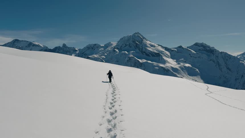 Man walking in a snow covered mountain valley