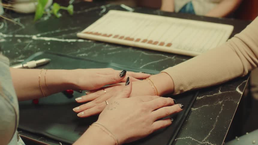 Pair of womans hands putting a bracelet on a persons wrist