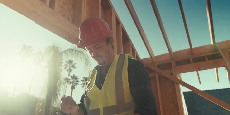A construction worker picks up a clipboard and looks around a new build