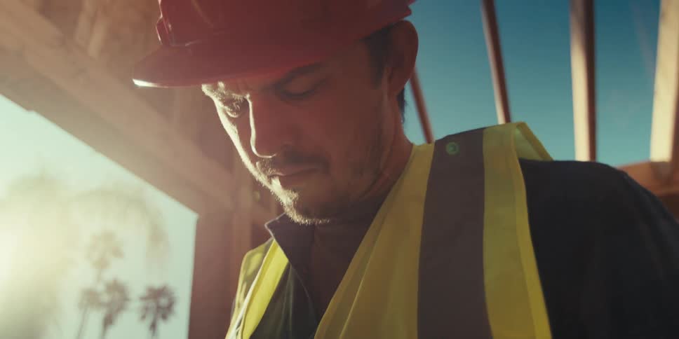 Male worker writes on a clipboard while on a construction site on a sunny day