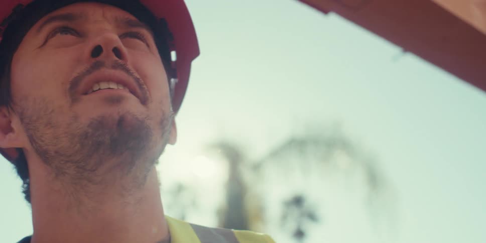 Male construction worker standing under a housing frame outdoors