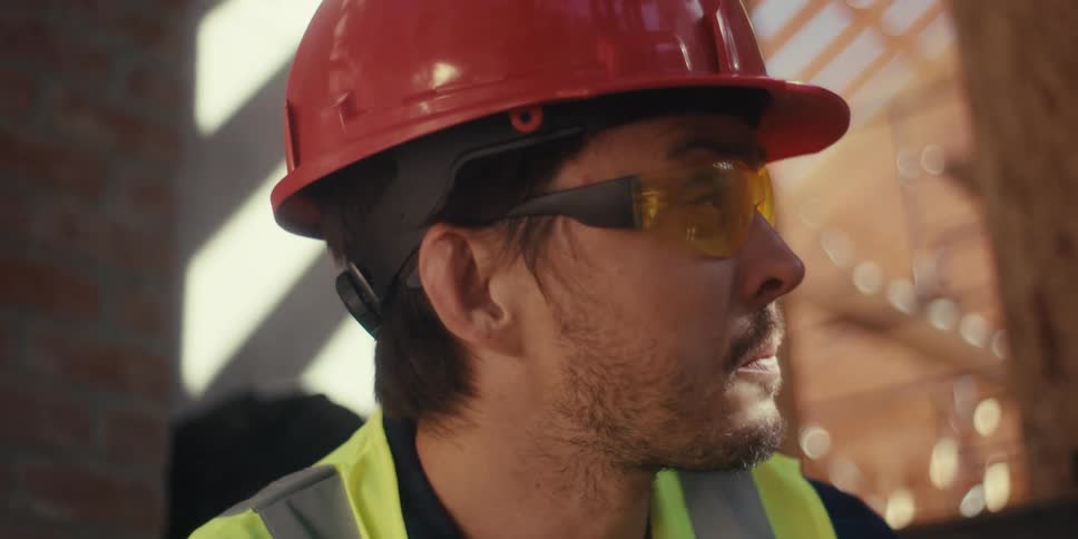 Portrait of a bearded man wearing a helmet and safety glasses at a construction site