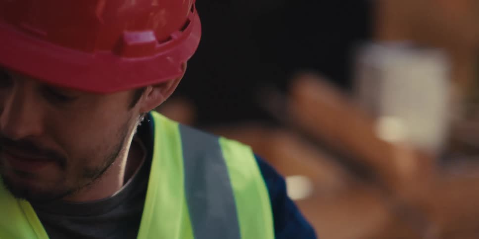 A construction worker lifts a two by four