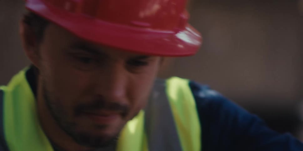 The man in the orange hard hat is using a level while he is working