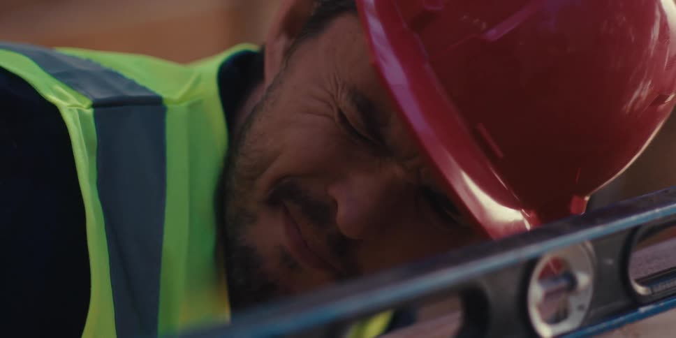 A construction worker eyes the leveler on the wood
