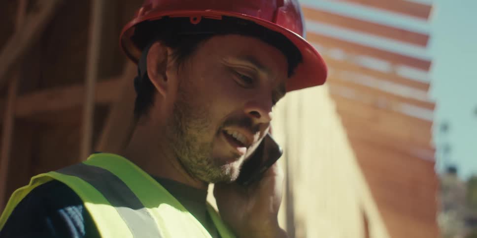 A construction worker reads his clipboard to someone on the phone