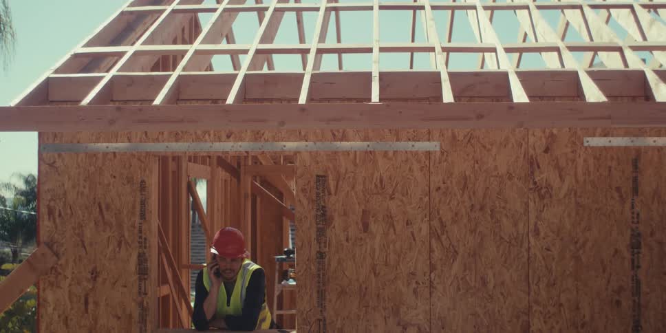 Man in helmet talking on cell phone while standing on unfinished construction site