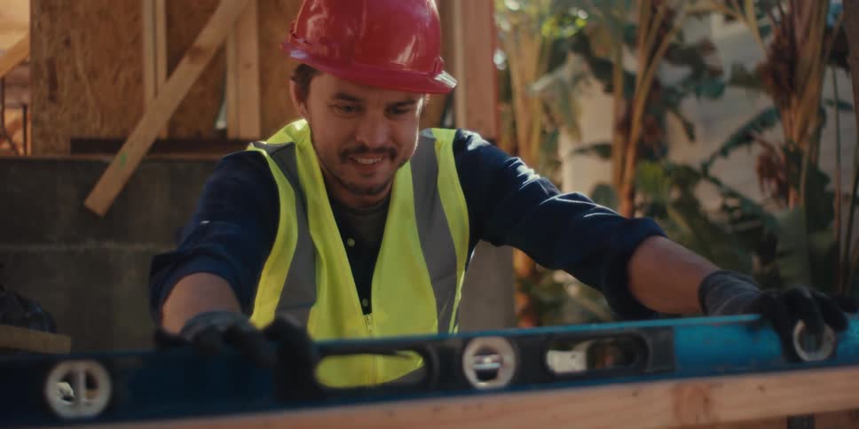 The worker uses a level on the beam