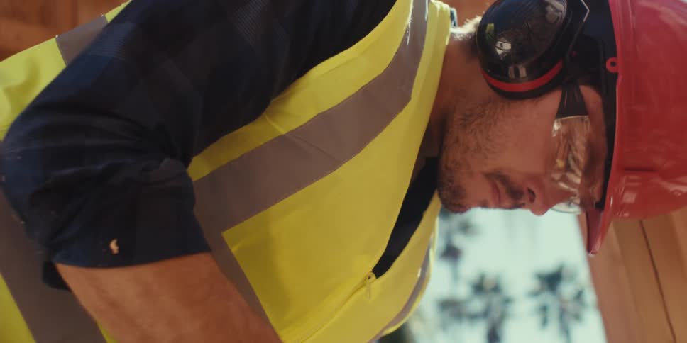 A construction worker is cutting wood with a saw