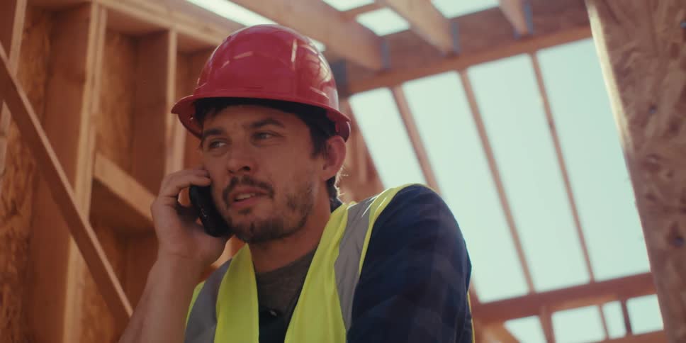 Construction worker is at the job site and talking on a phone