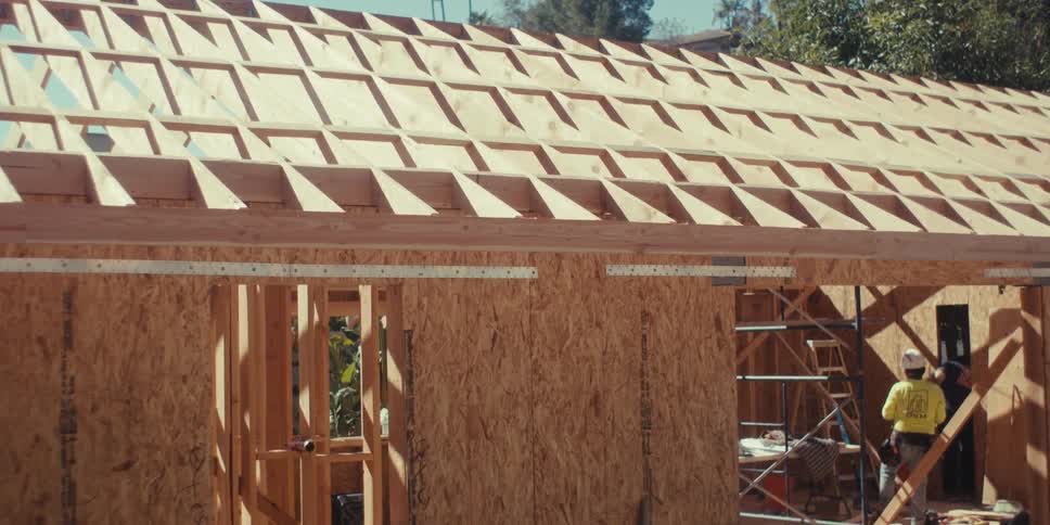 Construction workers build a houses wooden framework on a sunny day