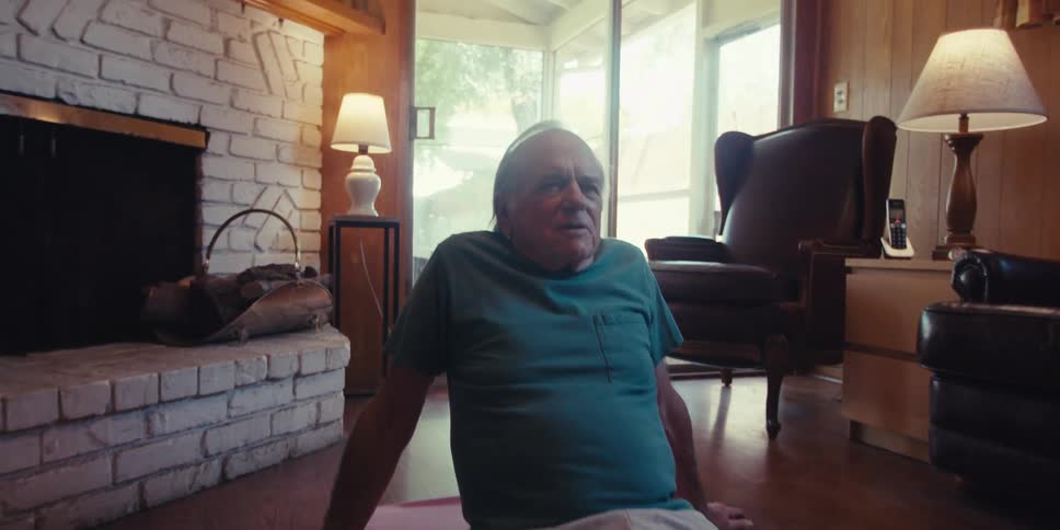Elderly man is doing a yoga pose inside of his living room