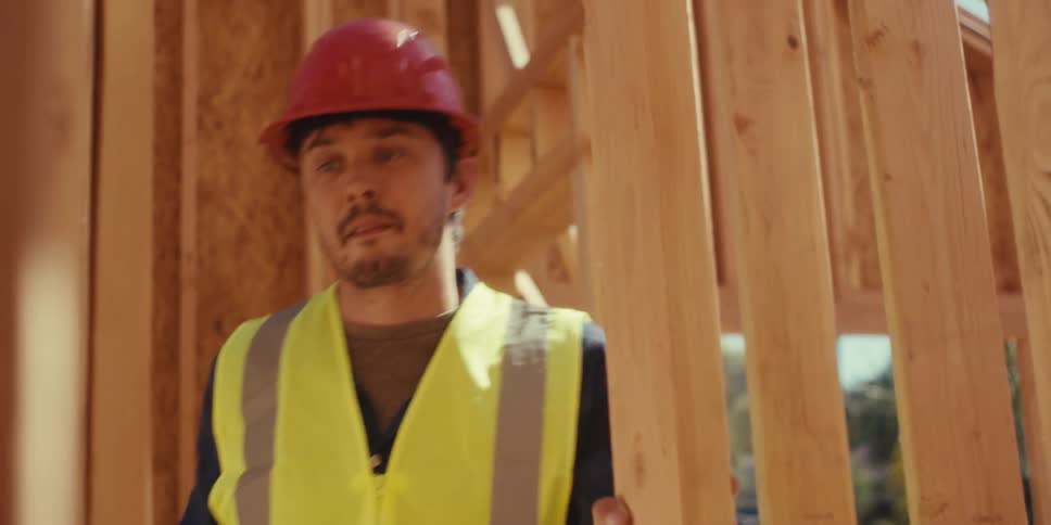The worker uses a measuring tape on the frame