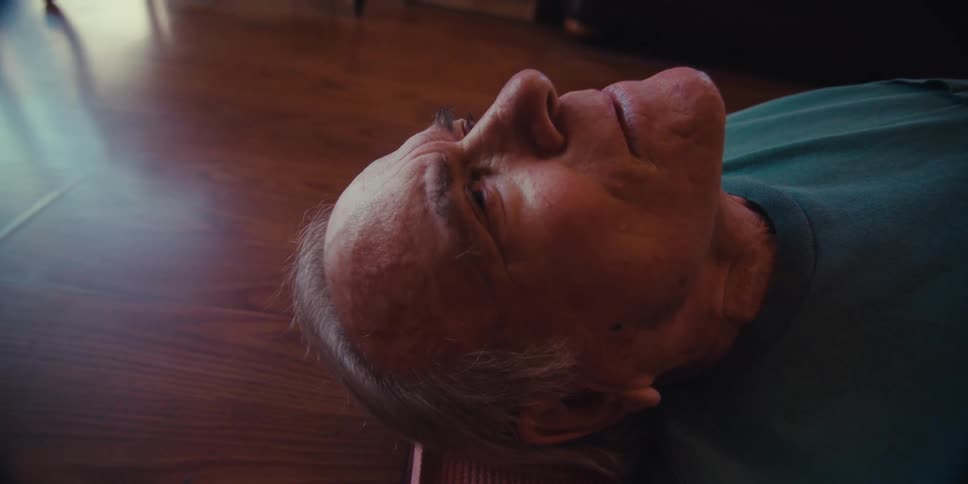 Elderly man is resting on a floor mat inside his home