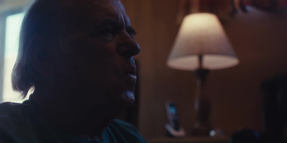 Elderly man sitting in his living room opens his eyes to whistle