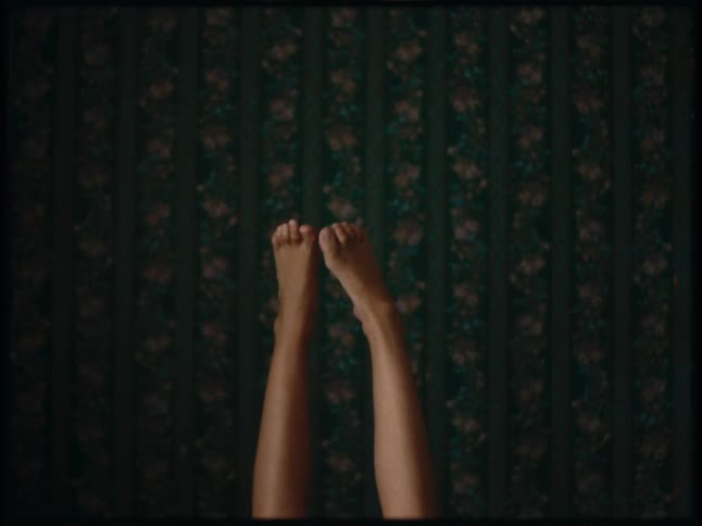 A persons feet extended upward against floral wallpaper