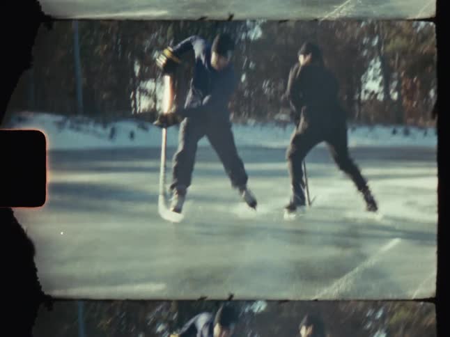 Two people playing an outdoor game of ice hockey