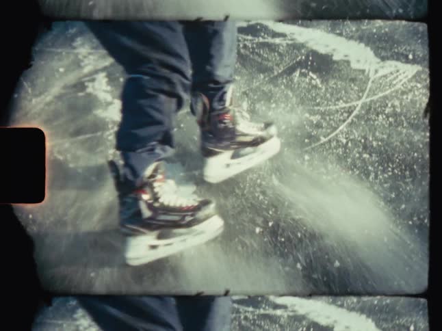 Person skating on ice creates a spray of ice when they slide to a stop on a winter day