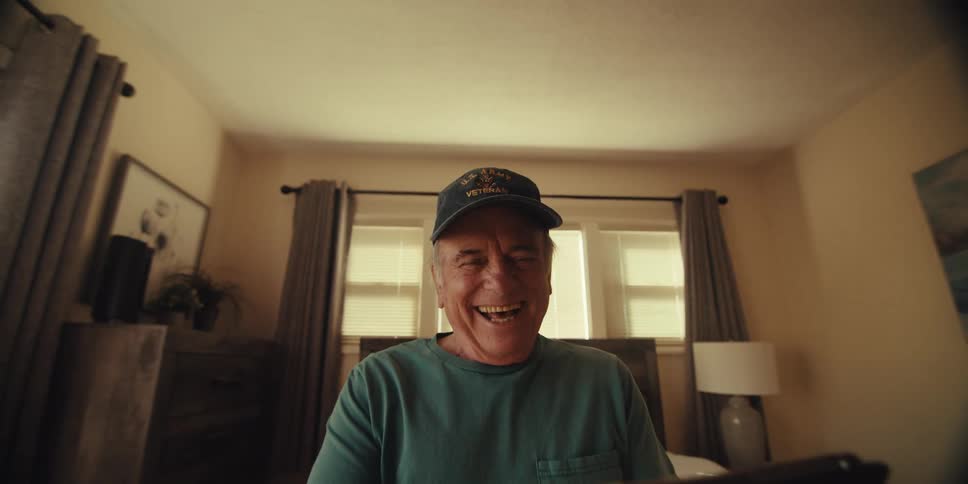 Smiling elderly man sitting on bed and holding a tablet