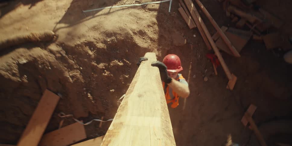Worker handing over a wooden slat to another construction worker