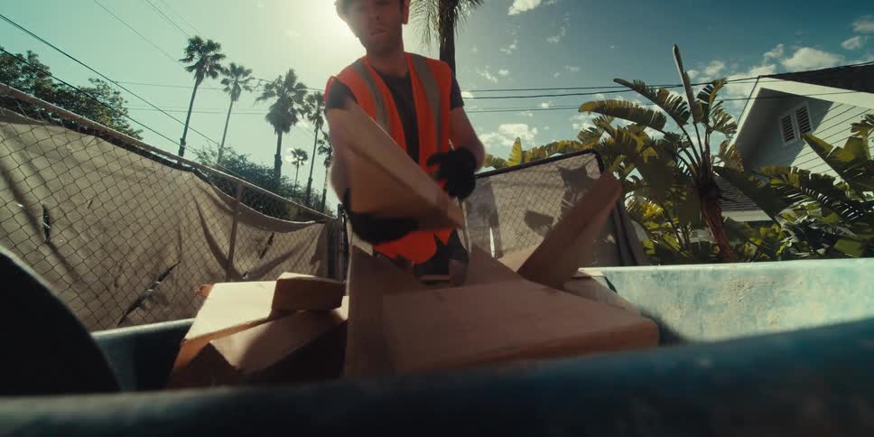 Construction worker placing a piece of wood into a blue bucket