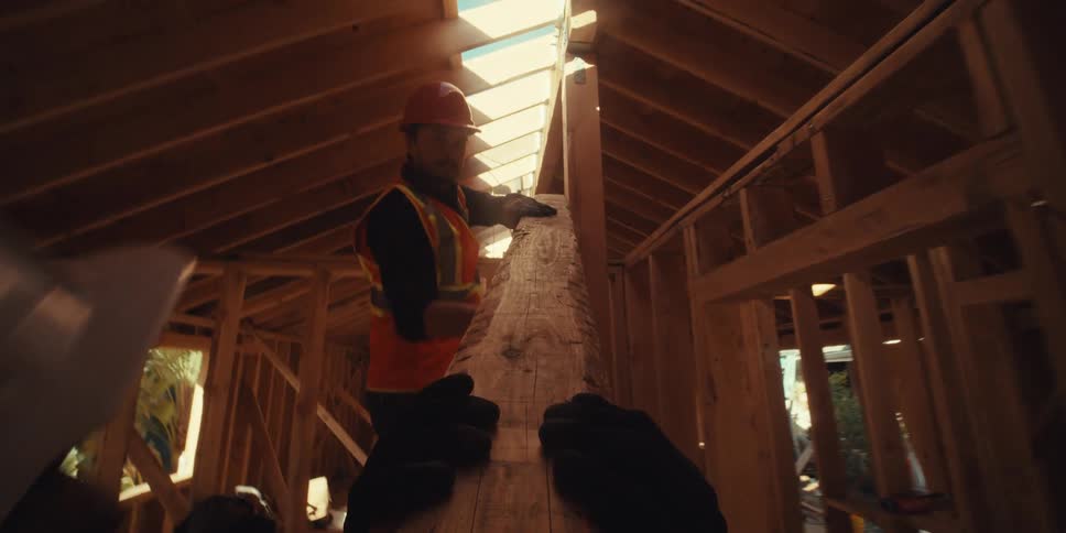 Man handing a wooden slat to another worker at a construction site