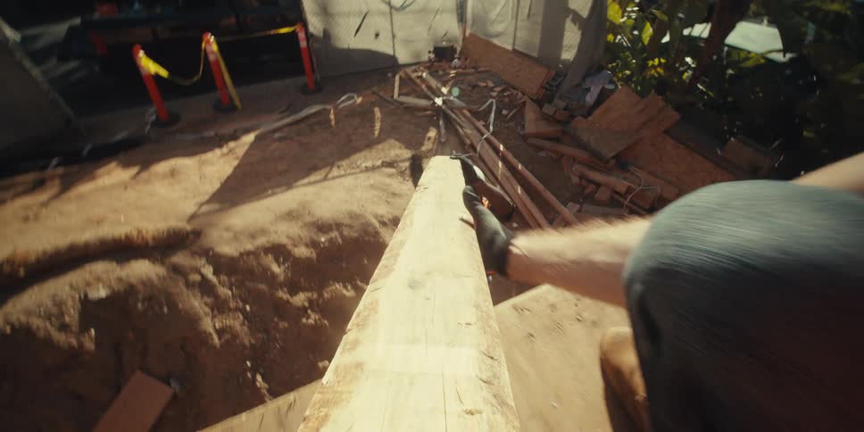 Worker handing another man a wooden slat at a construction site