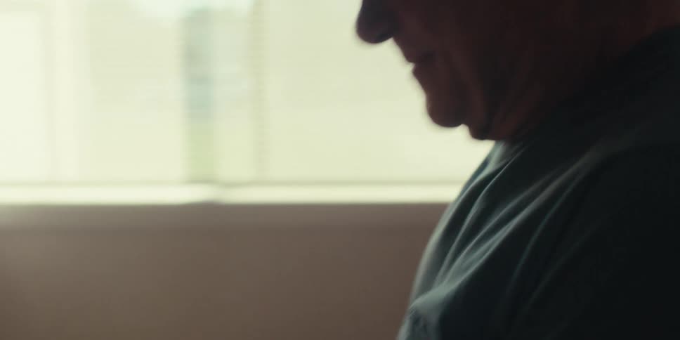 The older man who is sitting down is looking at the screen of his tablet