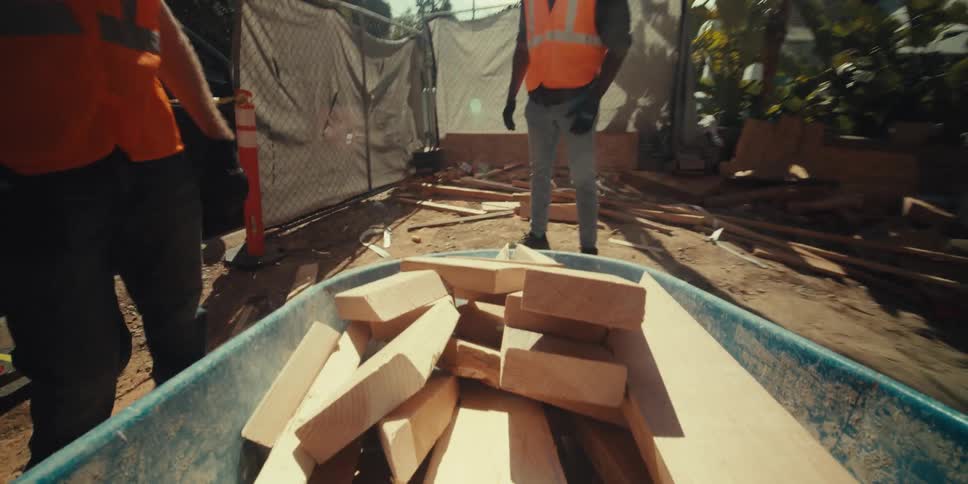 Workers remove planks of wood form the wheelbarrow
