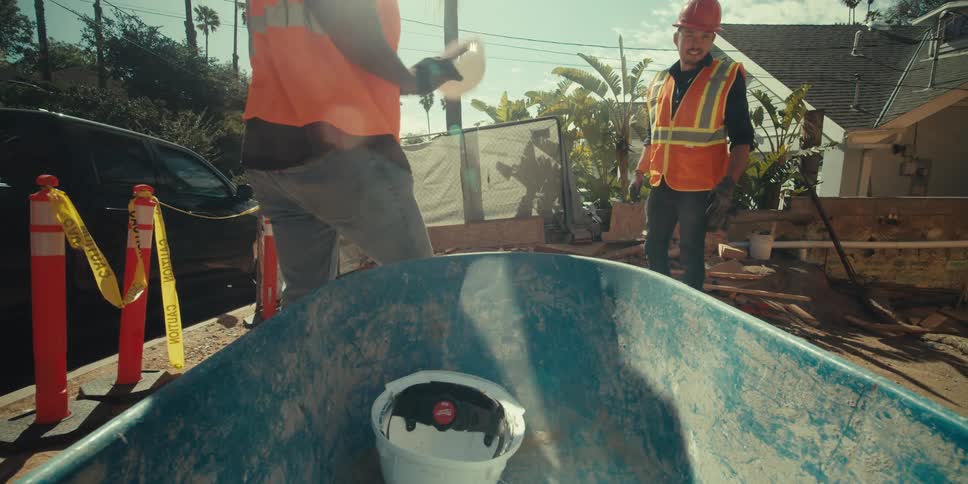Construction workers grab their hard hats from the wheelbarrow