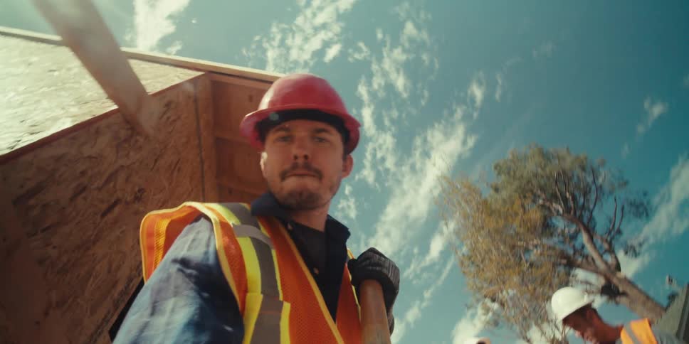 A construction worker wearing a hardhat and a vest using a shovel