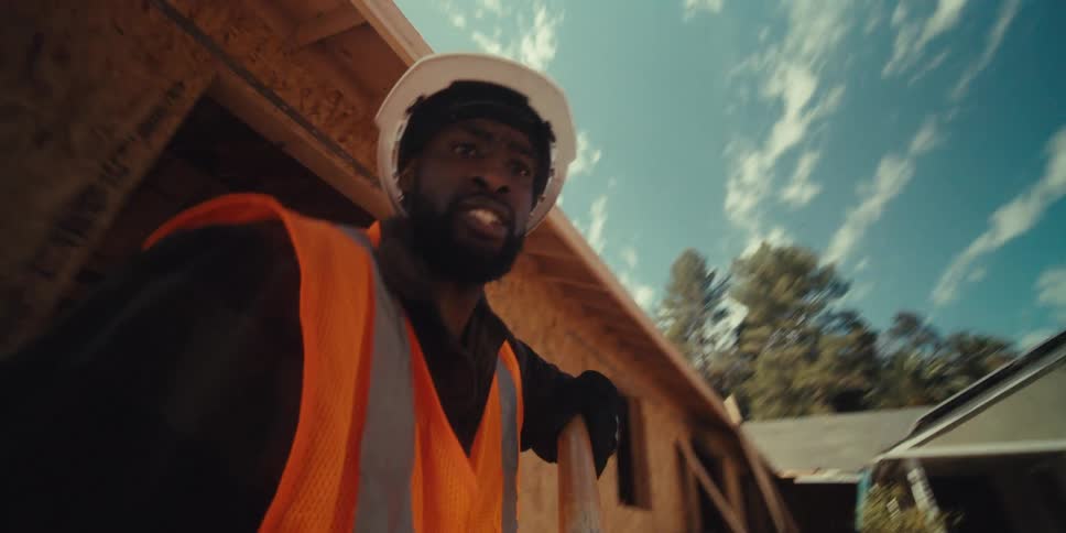 A construction worker digs into the ground while two other employees stand there and watch