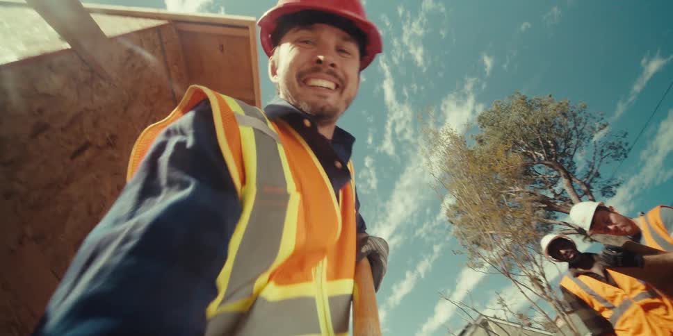 A worker wearing a red hard hat using a shovel on a construction site