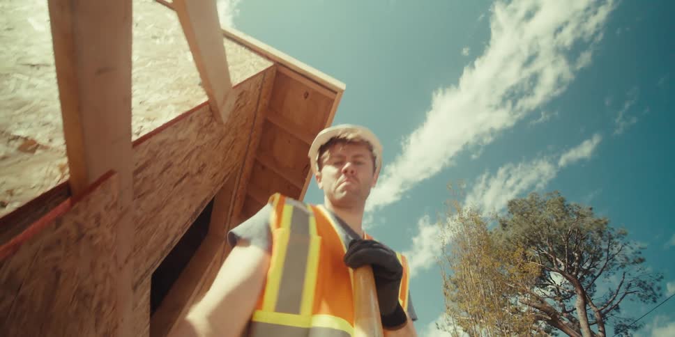 A worker in a hardhat and vest digs with a shovel at a construction site