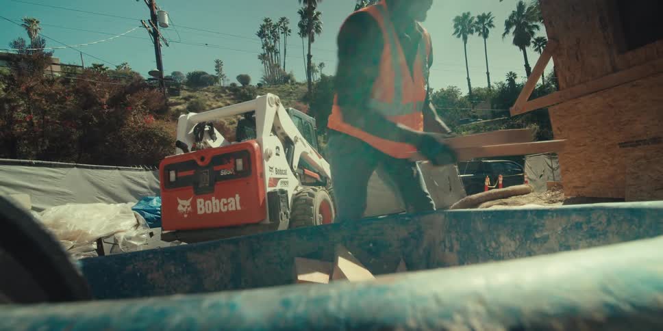 A construction worker unloading wooden scraps from a wheelbarrow