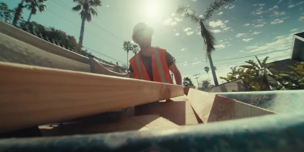 A construction worker pushes the wood filled wheelbarrow
