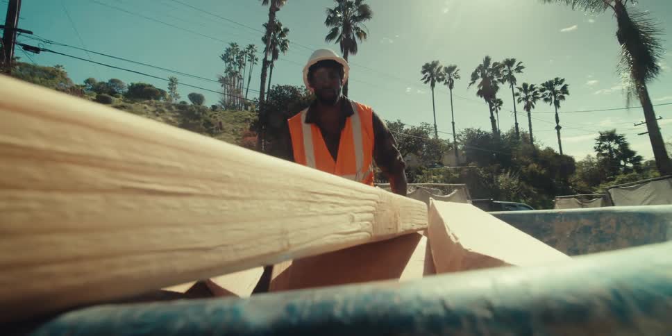 Man carrying a construction trolley with pieces of wood