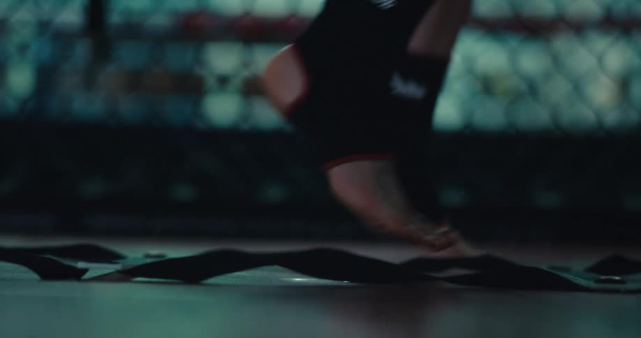 A person performs agility ladder drills in a dimly lit gym
